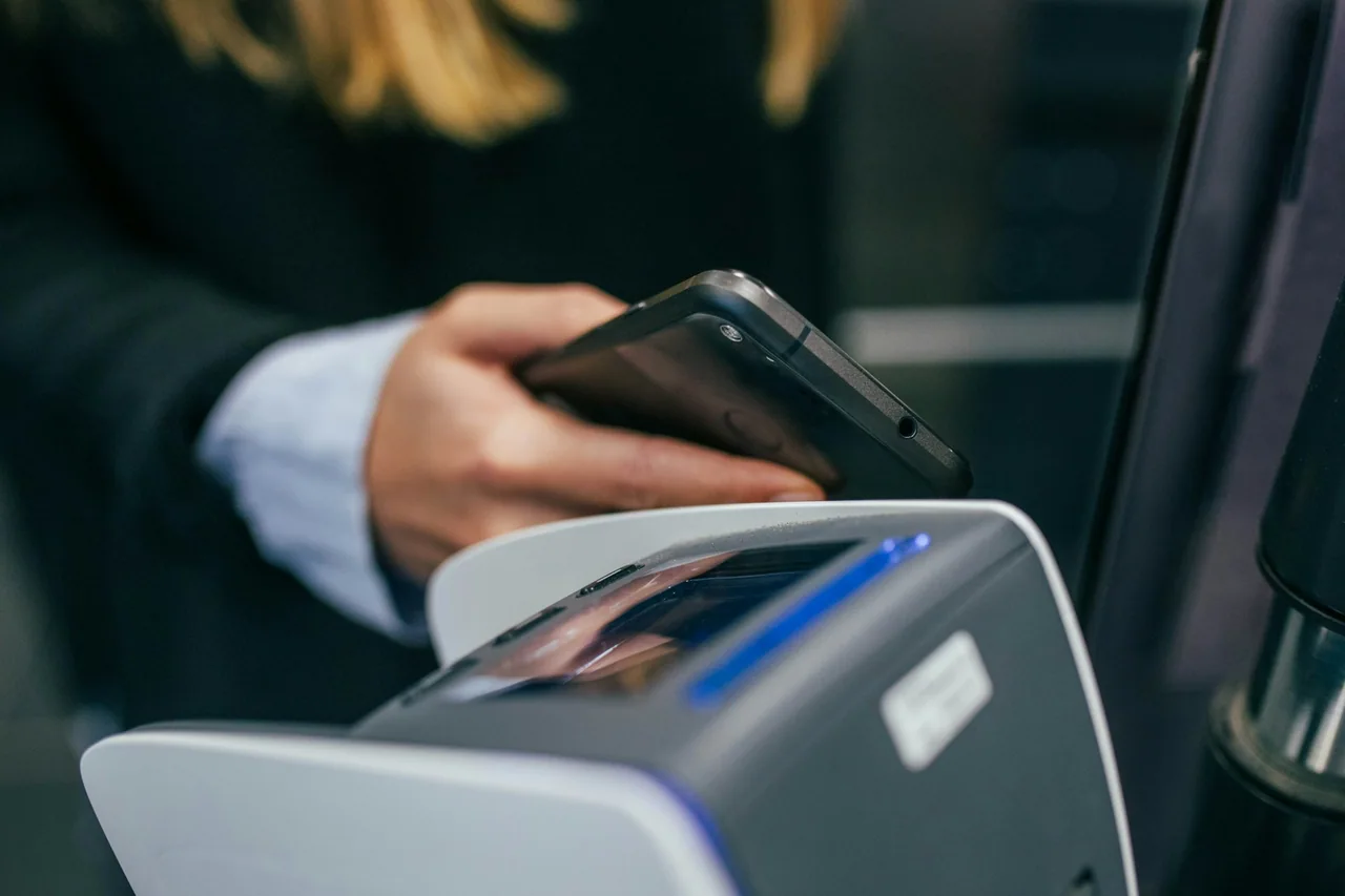 A customer holds a smartphone near a payment terminal.