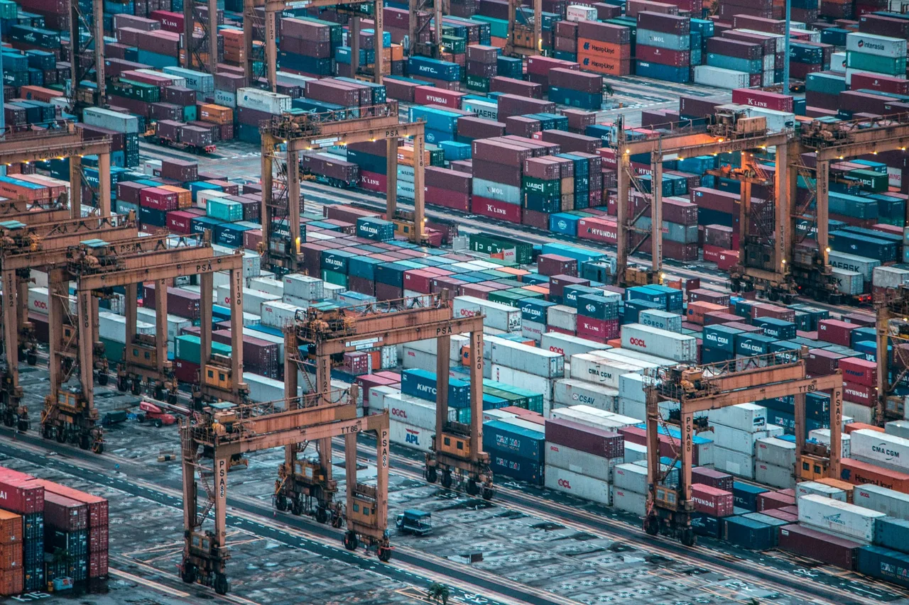 Rows of shipping containers and cargo cranes at a port in Singapore.