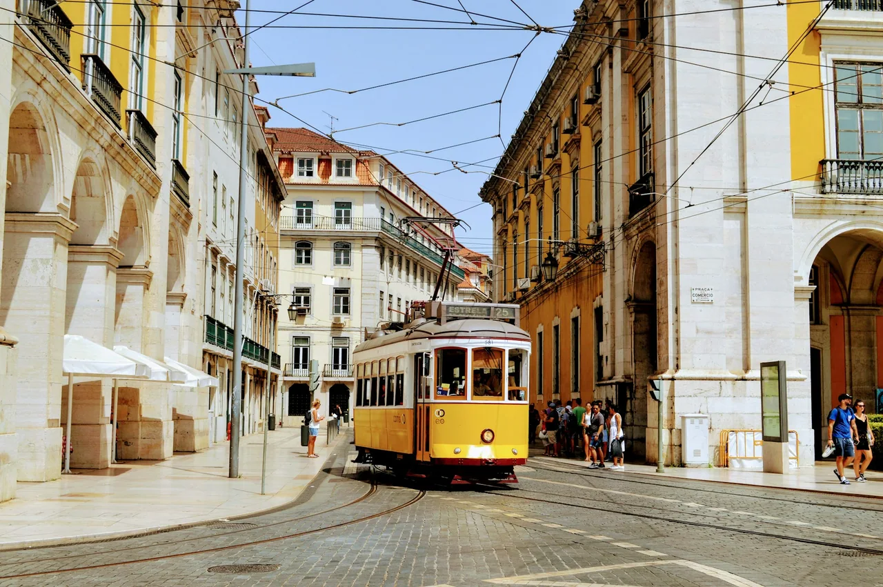 A yellow tram travels between historic buildings in Lisbon.