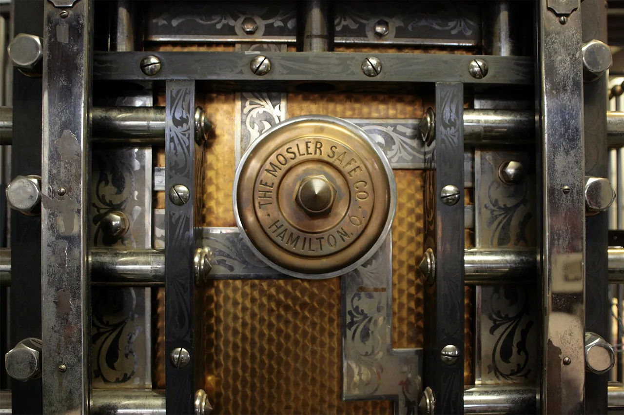 Close view of the locking mechanism on an old metal bank vault door.