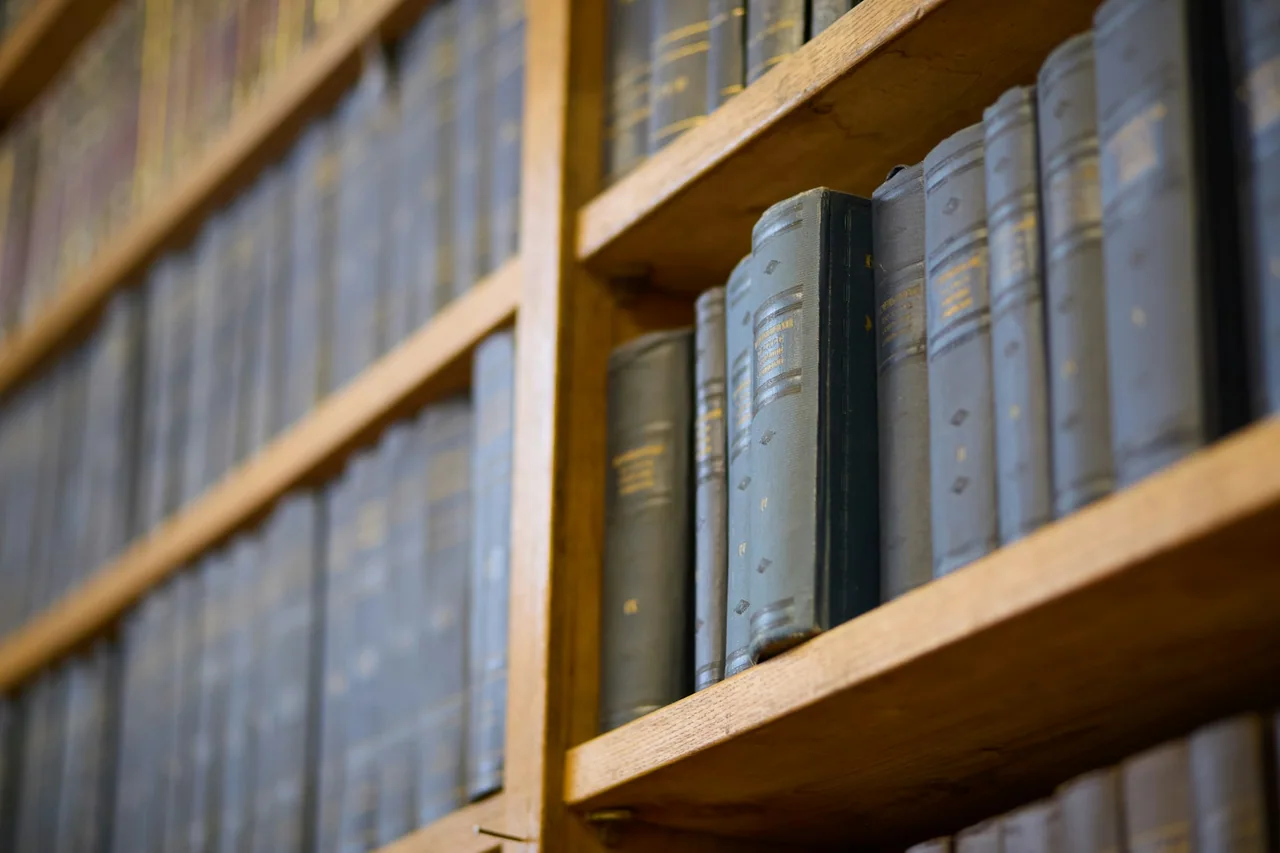 Rows of old books on wooden shelves