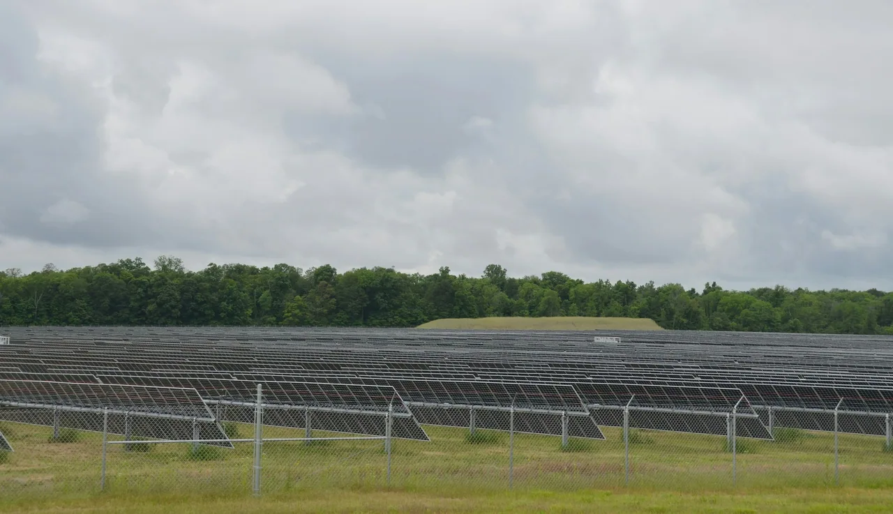 Rows of solar panels beneath a cloudy sky.