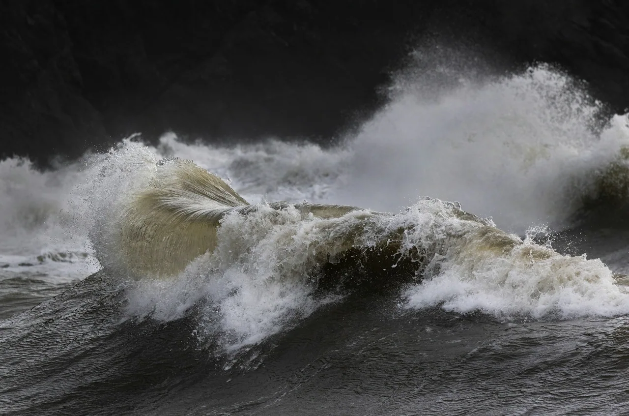 Large storm waves breaking against a rocky coast.