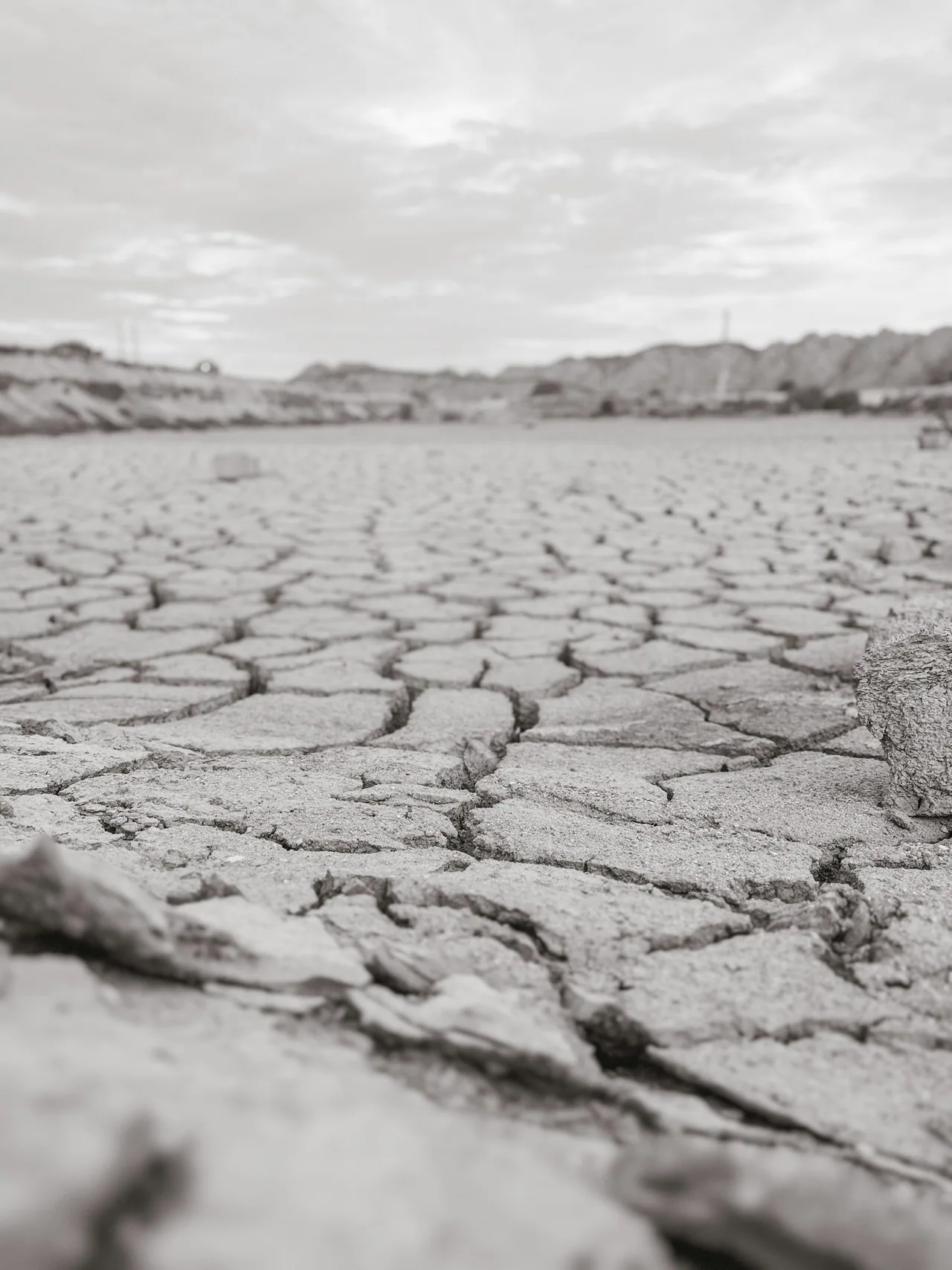 Cracked dry earth beneath a cloudy sky.