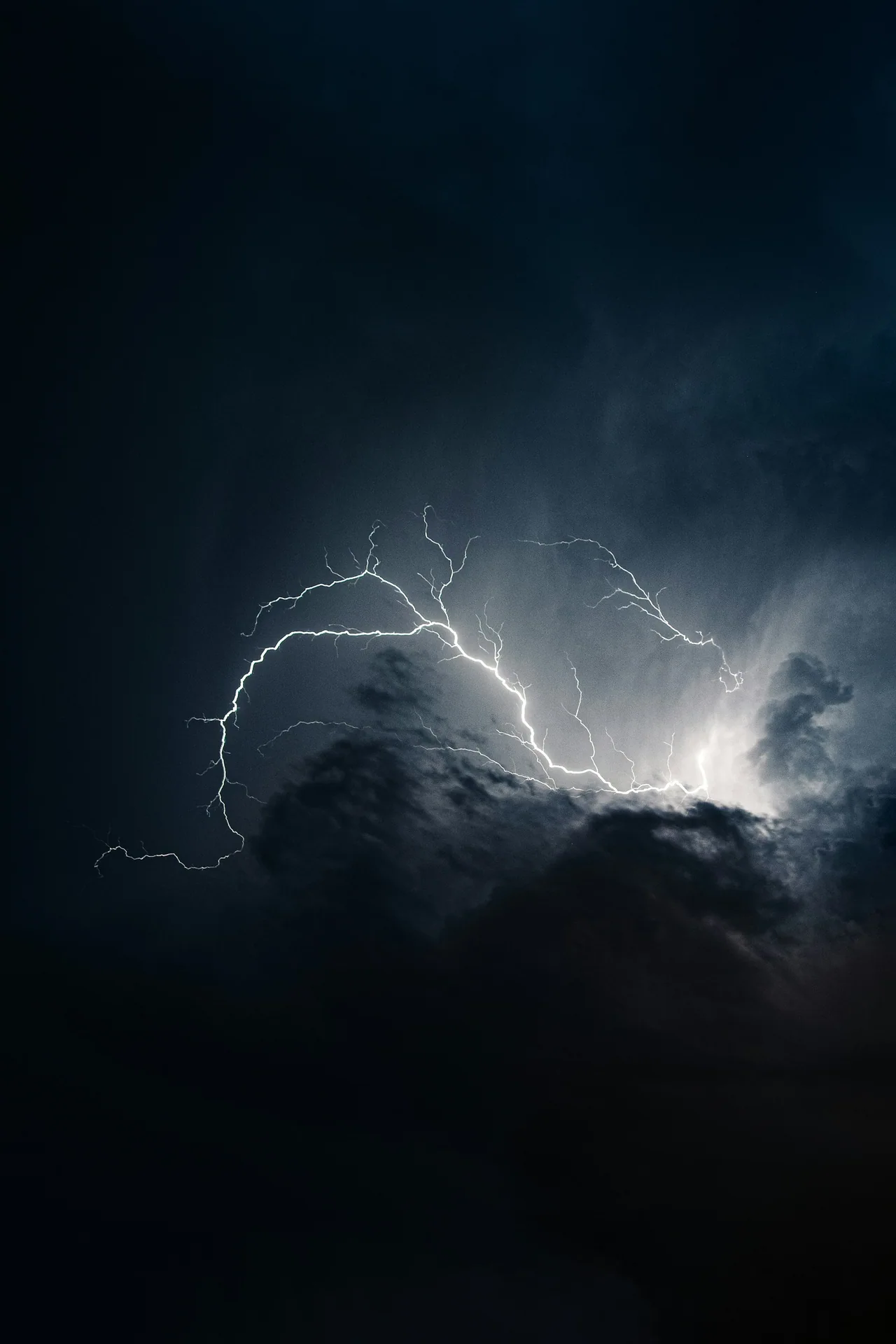 Lightning beneath dark thunderstorm clouds.